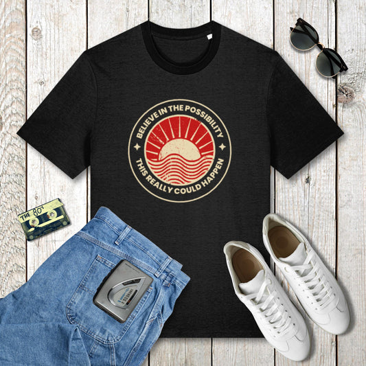 Black t-shirt with a red and gold graphic design on a wooden surface with jeans, sneakers, and sunglasses.