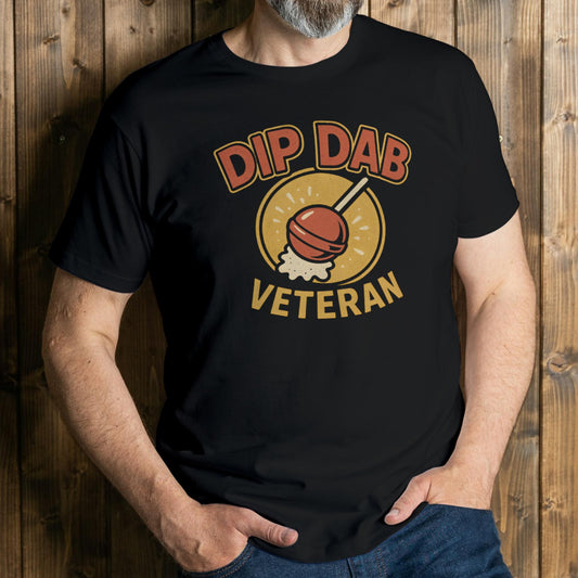 Person wearing a black t-shirt with 'Dip Dab Veteran' graphic design against a wooden background