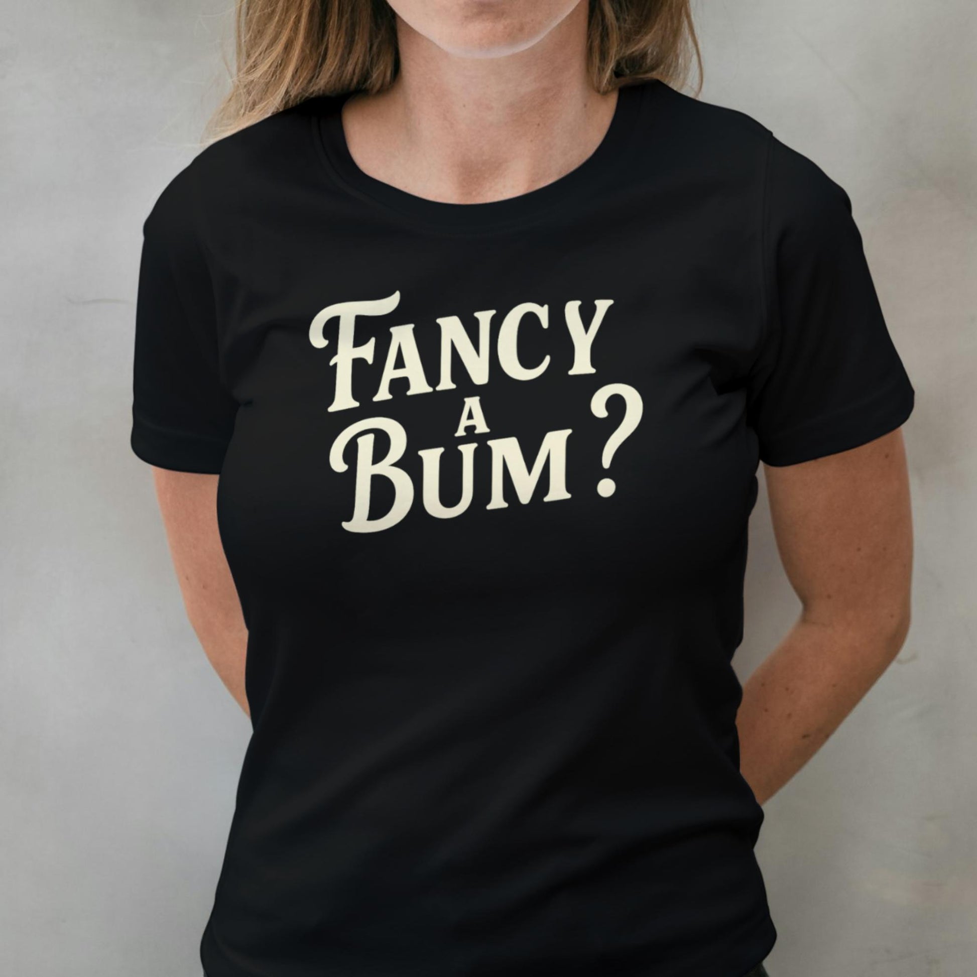 Person wearing a black t-shirt with 'Fancy A Bum?' text in white.