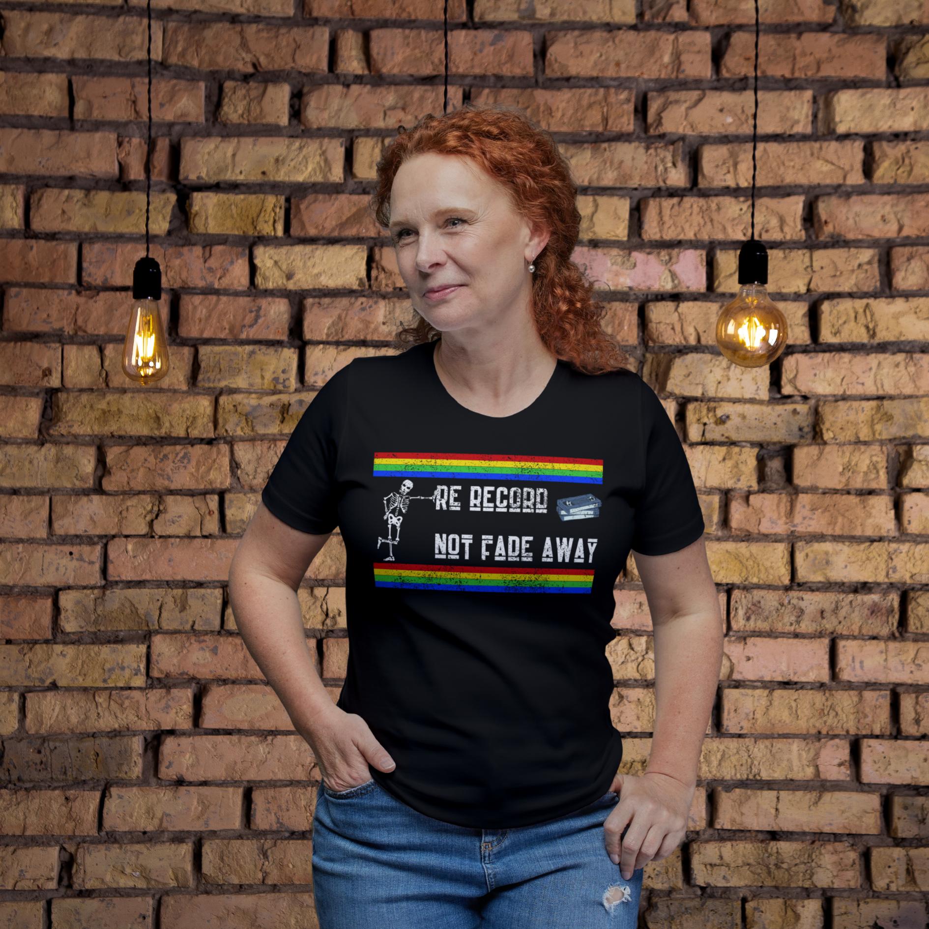 Woman wearing a black t-shirt with rainbow design and text, standing against a brick wall.
