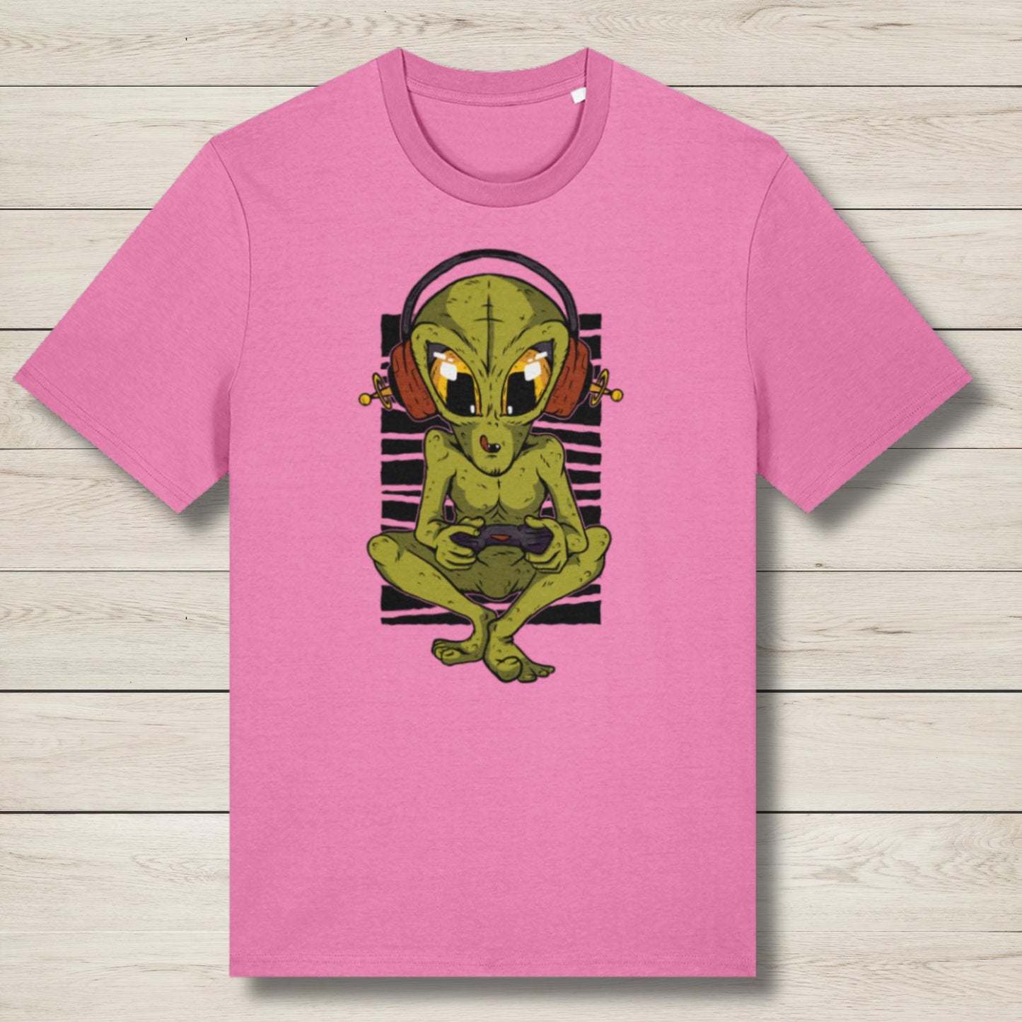 Pink t-shirt with a green alien graphic on a wooden surface