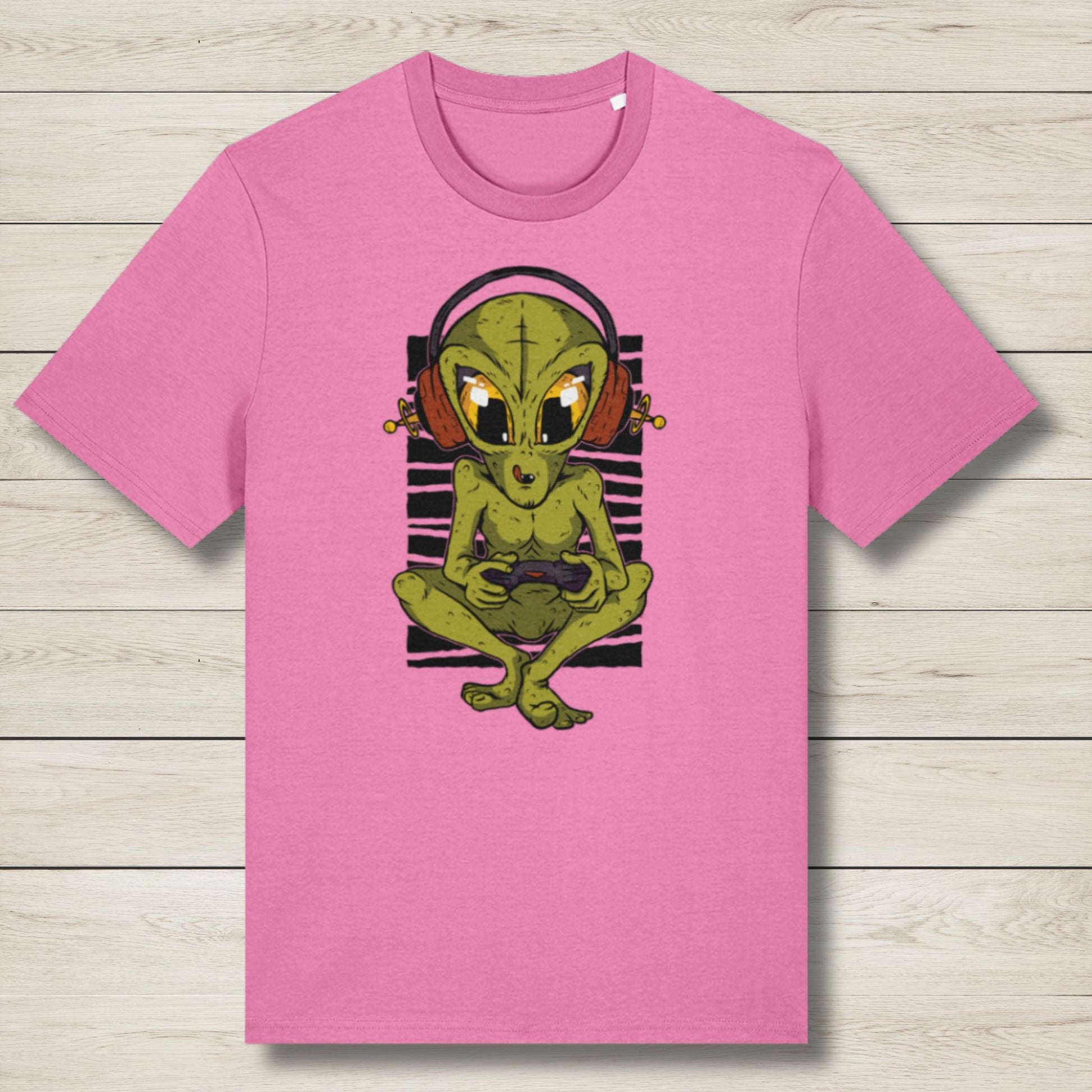 Pink t-shirt with a green alien graphic on a wooden surface