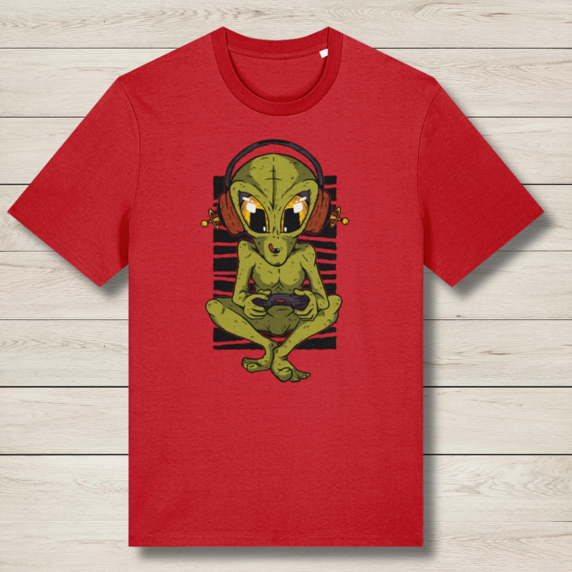 Red t-shirt with a green alien graphic on a wooden surface