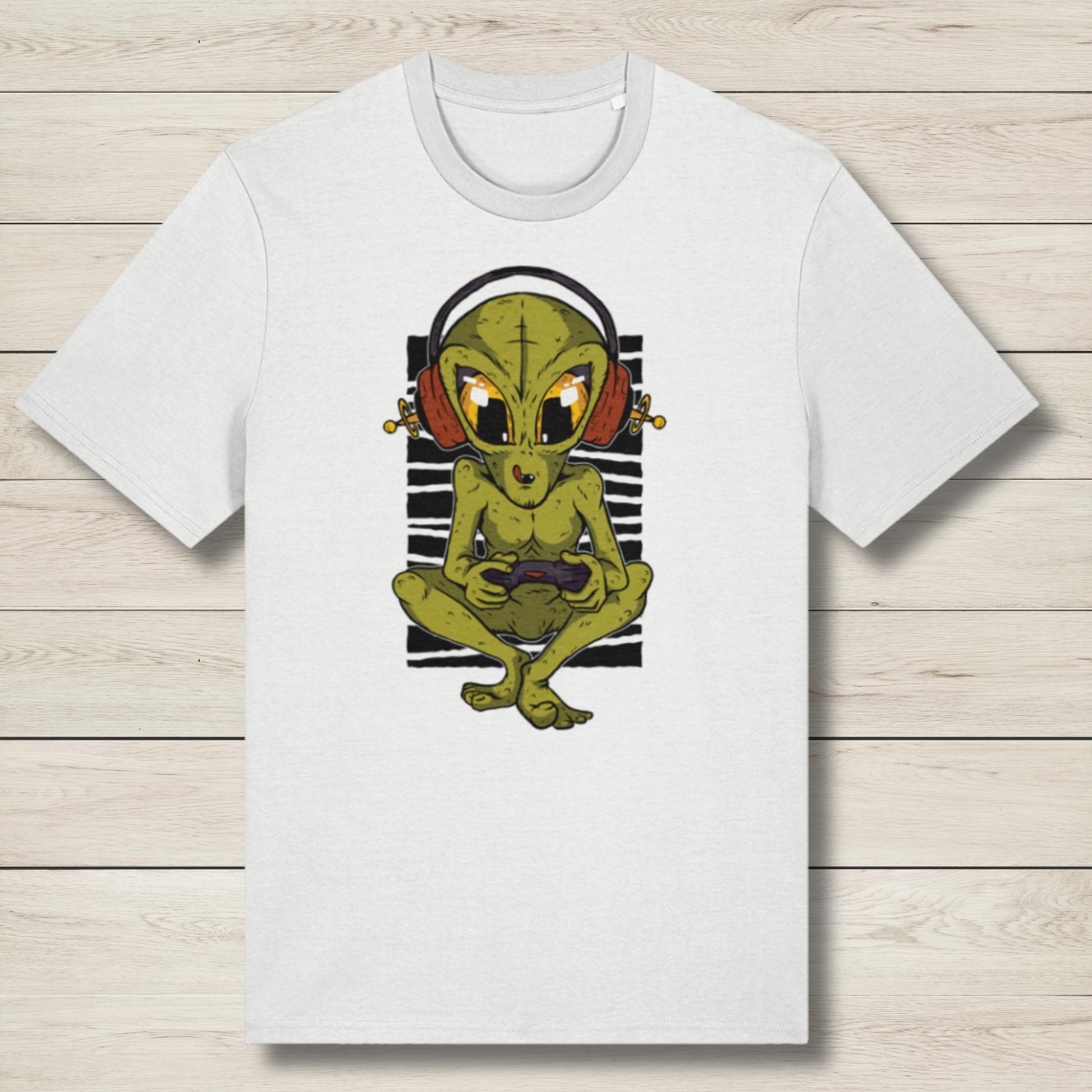 White t-shirt with a graphic of a green alien wearing headphones on a wooden surface