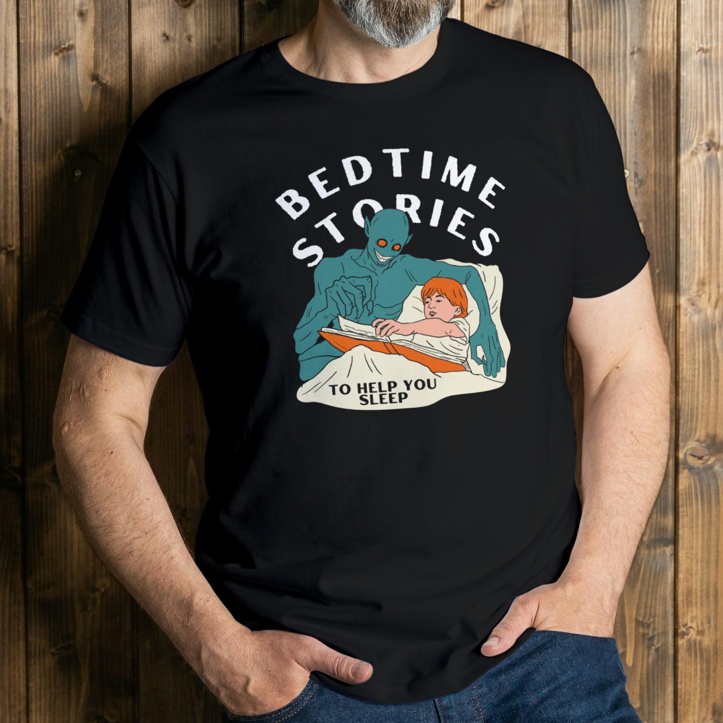Person wearing a black t-shirt with a graphic of an alien reading a bedtime story to a child, set against a wooden background.
