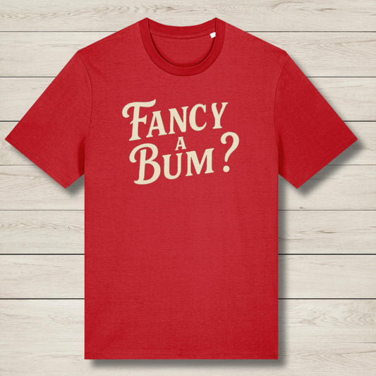 Red t-shirt with 'Fancy A Bum?' text on a wooden surface