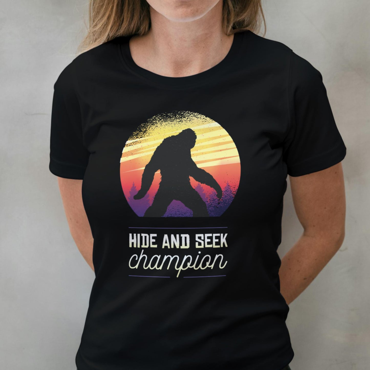 woman wearing a black t-shirt with a 'Hide and Seek Champion' graphic design.