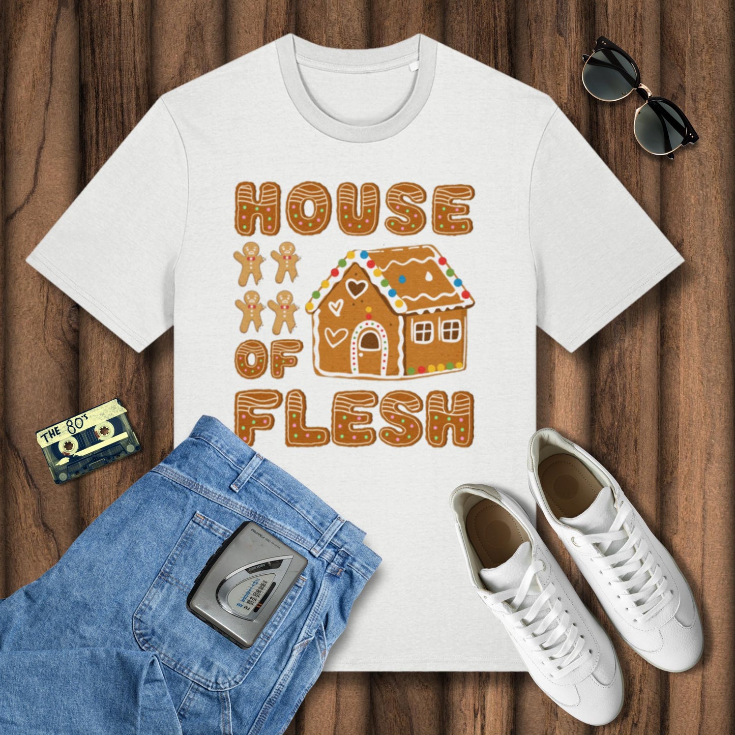 White t-shirt with 'House of Flesh' design on a wooden surface with jeans, sneakers, and sunglasses.