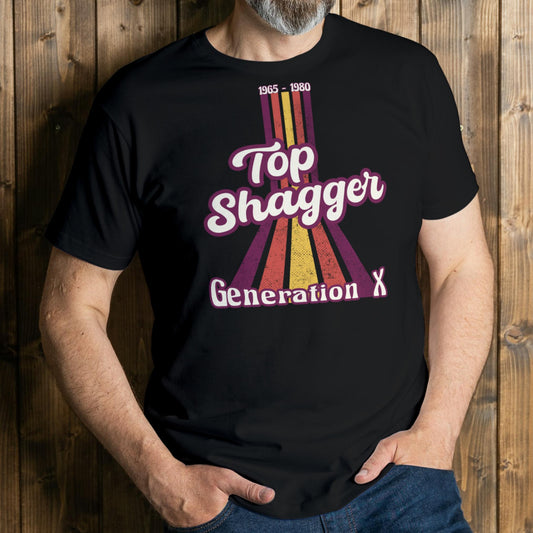 Person wearing a black t-shirt with 'Top Shagger Generation X' design against a wooden background