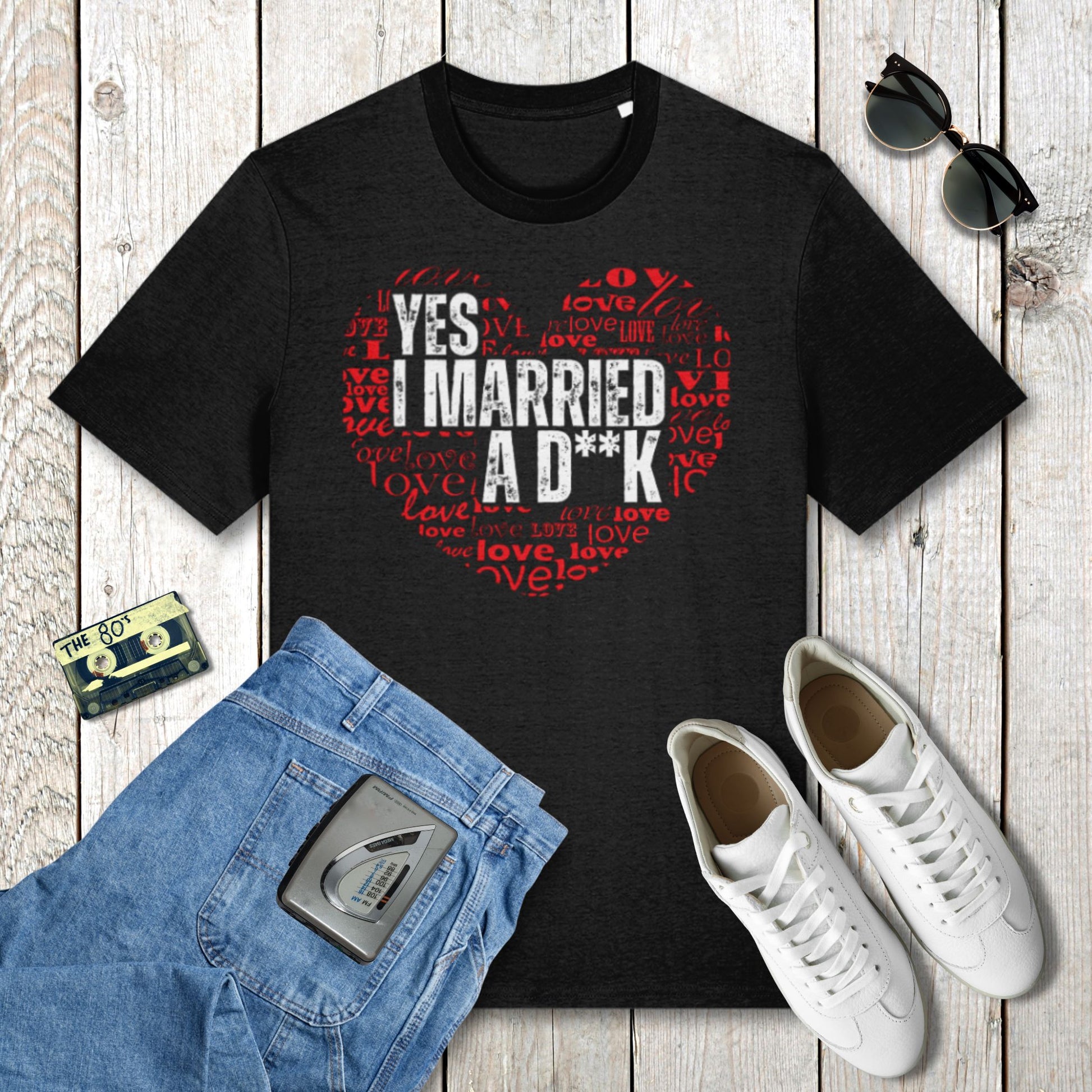 Black t-shirt with graphic design on a wooden surface with jeans, sneakers, and sunglasses.