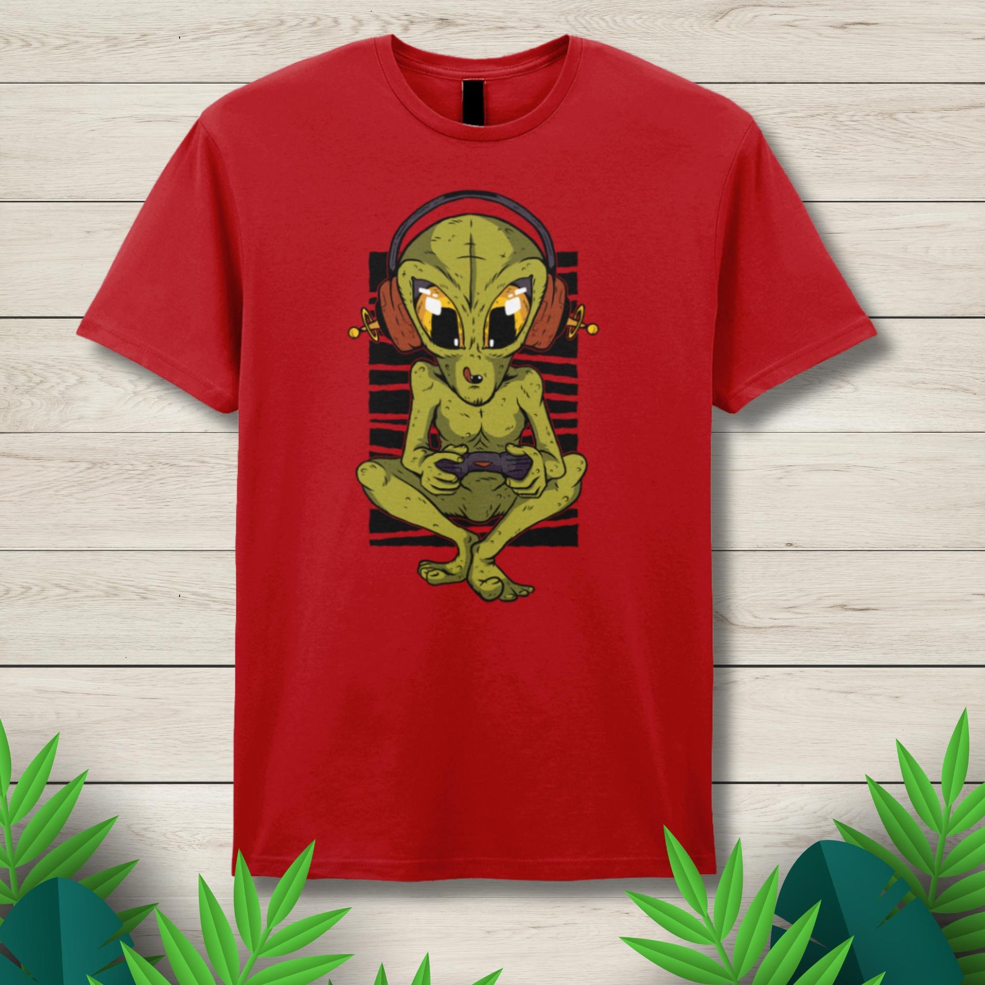 Red t-shirt with a green alien graphic on a wooden surface