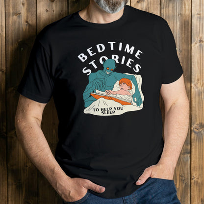 Person wearing a black t-shirt with a graphic of an alien reading a bedtime story to a child, set against a wooden background.