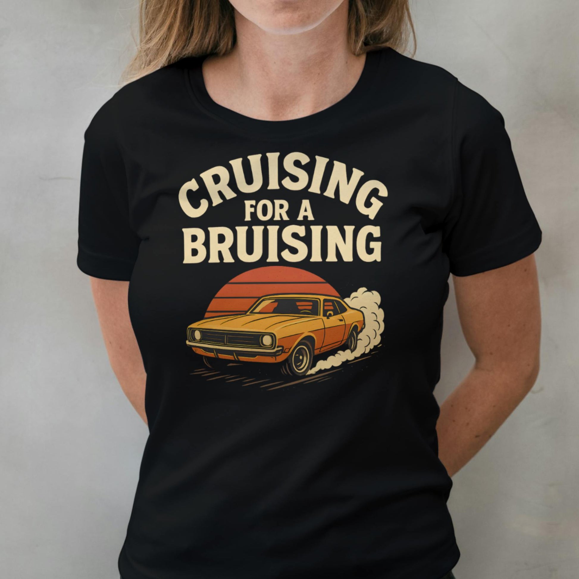 Person wearing a black t-shirt with a graphic and text 'Cruising for a Bruising' on a plain background