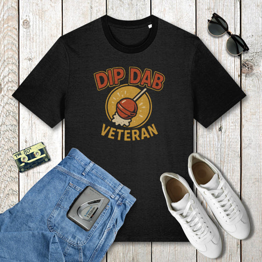 Black t-shirt with 'Dip Dab Veteran' graphic on a wooden surface with jeans, sneakers, and sunglasses.
