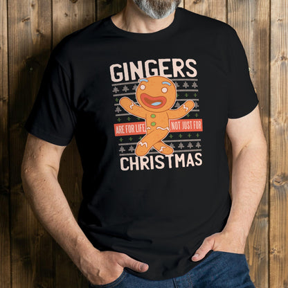 Person wearing a black t-shirt with a gingerbread man graphic and text against a wooden background