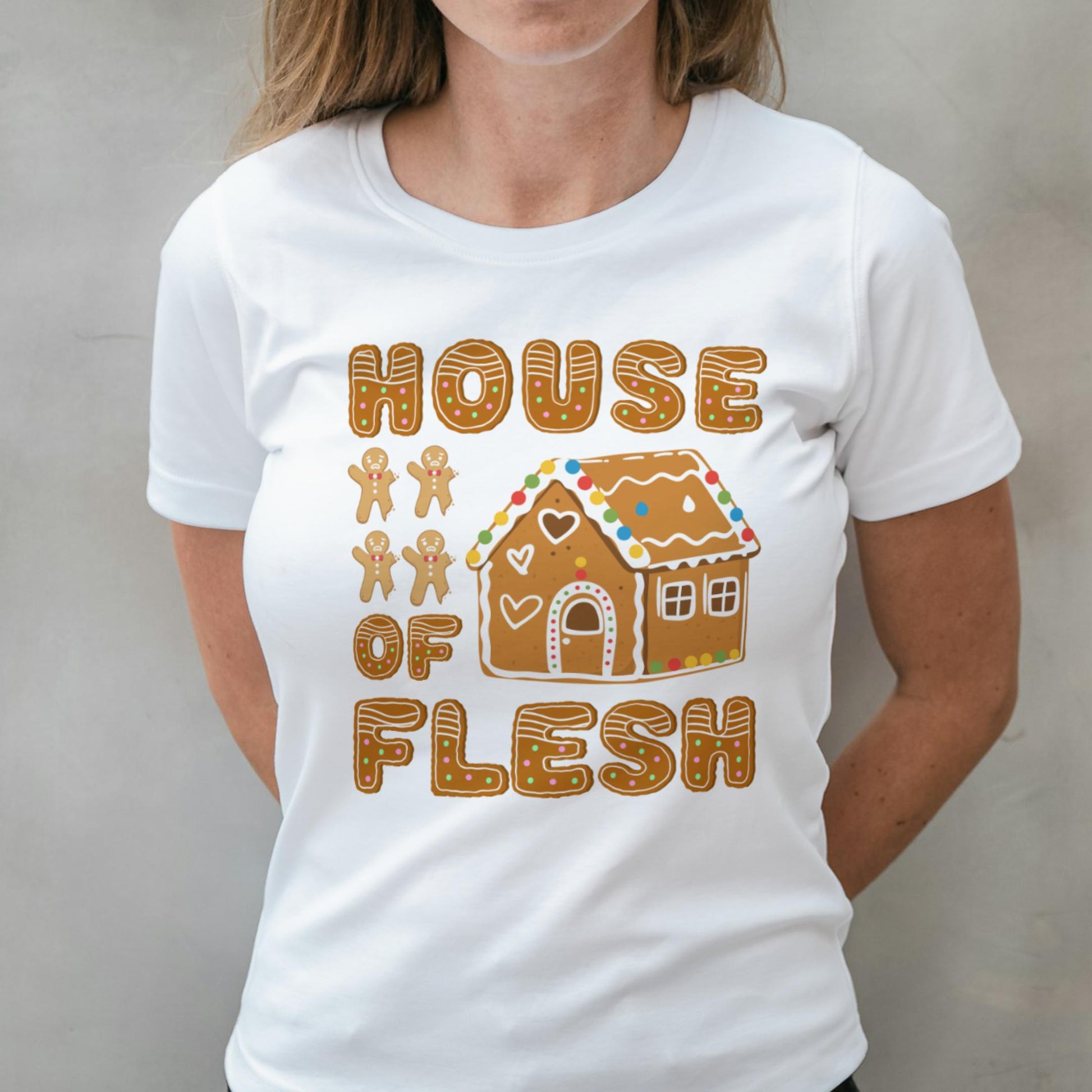 White t-shirt with a gingerbread house design and text on a plain background